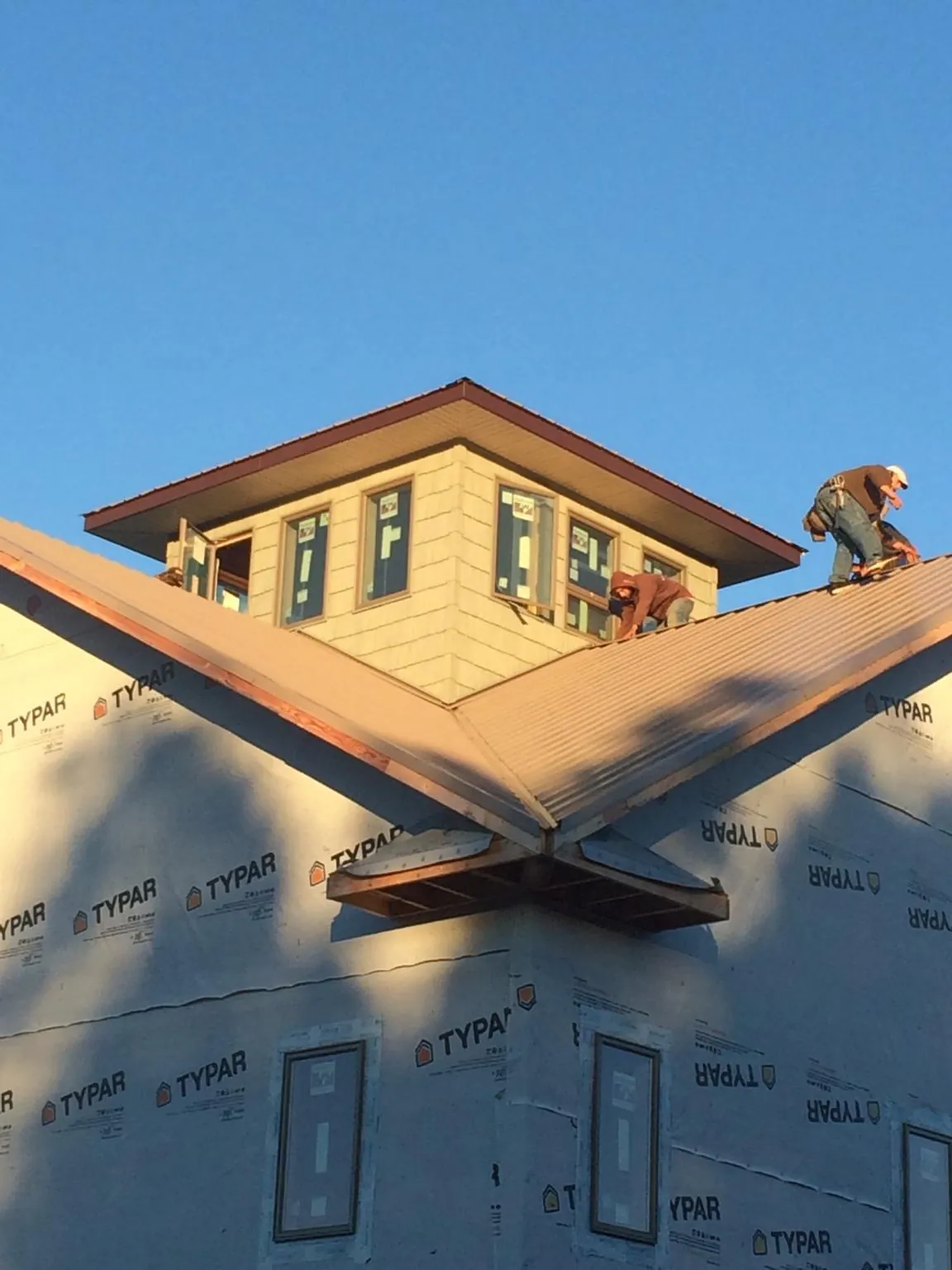 Roofers working around a rooftop cupola on a new metal roof at sunset — Roof Waterproofing in Avoca by Roofing Brothers